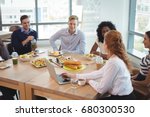 Business colleagues discussing while sitting around breakfast table at office cafeteria