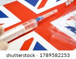 Small photo of syringe with a vaccine is held by hand in a glove on background of the England flag, vaccine against coronavirus, Operation Warp Speed, AstraZeneca vaccine