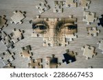 Small photo of Jigsaw Puzzle Of Female Face Mona Liza La Gioconda from Leonardo Da Vinci, from ancient painting on wooden background, closeup
