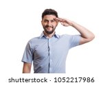 Portrait of handsome man. Young black haired guy with facial hair in blue casual shirt saluting with hand at forehead