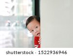 Adorable little boy hide behind a corner room. Baby playing peekaboo game indoor.