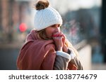 Woman breathing on her hands to keep them warm at cold winter day