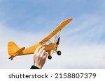 Yellow plane above the sky. Man launching radio controlled airplane