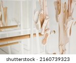 Small photo of Clothing rail with pointes, ballet body suit and dress. Ballet class or ballet store concept. Light interior with barre and ballet accessory