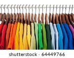 Rainbow colors. Choice of casual clothes on wooden hangers, isolated on white.