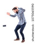 Small photo of Shocked sloppy clumsy bearded man dropping mobile phone falling on the ground in mid air. Full body isolated on white background.