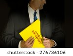 Small photo of Top Secret Classified business, legal and government concept showing a man in a black suit pulling a Top Secret folder dossier out of his jacket. Dramatic lighting highlights the Top Secret folder