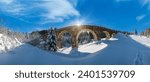 Small photo of Stone viaduct (arch bridge) on railway through mountain snowy fir forest. Snow drifts on wayside and hoarfrost on trees and sunshine in sky.
