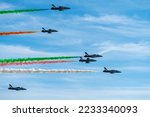 Air show of the Frecce Tricolori aerobatic team of the Italian Air Force with colored smoke trails in front of partly clouded sky