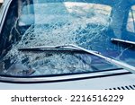 Broken car windshield and windshield wiper. Blue tint