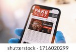 Small photo of Online Corona Fake news on a mobile phone. Close up, man reading Fake news or articles about covid-19 in a smartphone screen application. Hand with gloves holding smart device. COVID19 nCov Outbreak.