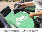 Hand inserting a DC CCS2 EV charging plug into electric car socket at charging station, Hypercharger or Supercharger.  Charge electromobility concept image.