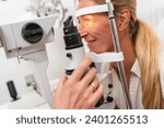 Small photo of Female patient undergoing an eye examination with a focus on her illuminated eye using a slit lamp at the clinic. Close-up photo. Healthcare and medicine concept