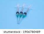clear plastic syringes with needles isolated against a light blue background
