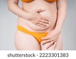 Small photo of Female belly with a scar from a caesarean section close-up on a gray background, body care concept