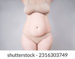 Small photo of Tummy tuck, flabby skin on a fat belly, plastic surgery concept on gray background