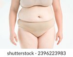 Small photo of Tummy tuck, flabby skin on a fat belly, plastic surgery concept on gray studio background