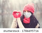 Christmas Woman in medical protective face mask making heart, winter portrait