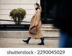 Side view beautiful woman walking street in fashionable spring or autumn clothes cashmere coat, jeans, loafers shoes and small bag. Full length Female model in motion, street style fashion