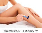 Beautiful, slim woman shaving legs, sitting on white background