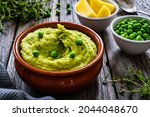 Puree - mashed potatoes with green pea in bowl on wooden table 