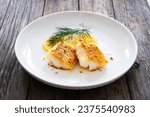 Small photo of Seared cod loin and sliced lemon on wooden table