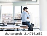 Small photo of Rearview shot of a careworn businessman looking out the window in an office.