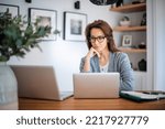 Small photo of Thinking woman sitting at laptops and hands on face. Careworn business woman working from home. Home office.