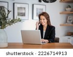 Shot of an attractive businesswoman using a laptop and having a call while working in her home office. Confident female wearing blazer. 