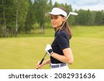 Small photo of Professional female golfer holding golf club on field and looking away. Young woman standing on golf course on a sunny day.