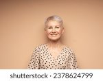 Small photo of Elderly smiling beautiful woman with a short pixie haircut in a beige dress