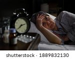 Small photo of Depressed senior woman lying in bed cannot sleep from insomnia