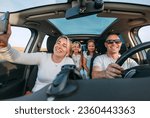 Small photo of Happy young couple with two daughters inside car during auto trop. They are smiling, laughing and taking selfies using smartphone. Family values, traveling, social media and new technology concepts.