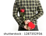 Image of the romantic guy holding a red rose and heart-shaped box behind his back