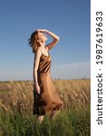 Small photo of Portrait of beautiful woman in silk camisole dress on windy summer day. Outdoor portrait with natural light.