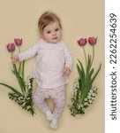 Small photo of Adorable five months old baby with pink spring tulips. Herald of spring. Baby and infant milestone session. Spring composition. Photoshoot of newborns. March 8 or Easter postcard concept.