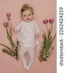 Small photo of Adorable five months old baby with pink spring tulips. Herald of spring. Baby and infant milestone session. Spring composition. Photoshoot of newborns. March 8 or Easter postcard concept.