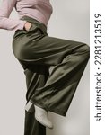 Small photo of Female model wearing tight viscose long sleeved top and wide green satin trousers. Classic, simple, comfortable yet stylish fashion. Studio shot.