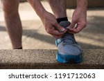 Small photo of Male athlete Runner tying running shoes or shoelace on footpath with sunset light and getting ready for run. Healthy lifestyle for teenager, middle age worker, and senior people or oldster.