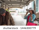 Small photo of Beautiful Asian rich woman with many shopping bag look down and mean to beggar or homeless old man in urban city. bad habit for high society or gentility to disgust the poor.