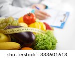 Healthy nutrition concept. Close-up of fresh vegetables and fruits with measuring tape lying on doctor's desk. 