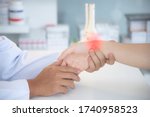 Small photo of Asian orthopaedic doctor doing physical examination in the patient with wrist pain at the clinic. Pain from tendinitis and sport injury. Selective focus at wrist with red hi light. Medical concept