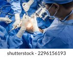 Small photo of Team of doctor or surgeon in blue gown inside operating room in hospital.Surgeon did total knee joint replacement surgery technology.Osteotomy with medical saw at orthopedic unit.Light background.
