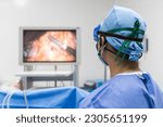 Doctor or surgeon in blue uniform looking at monitor screen in operating room at hospital.Minimal invasive gall bladder surgery in stone.Medical technology with white space.Computer assist device.