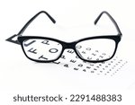 Eyeglasses with eye test table on white, optometrist concept and eye test