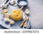 Small photo of Homemade garlic paste in a jar with peeled garlic, salt, crusher and garlic heads, with copy space