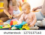 Small photo of Group of babies with mothers playing toys at playgroup