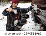 Small photo of Adult Woman Struggling to Install Tire Chains on Her Car in Unfriendly Weather, Battling Snowfall and Overcoming the Challenge with Determination