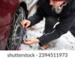 Small photo of Confident Mid Adult Woman Close-Up Installing Tire Chains in Unfriendly Cold Weather with Snowfall