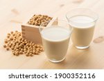 Soy milk in a glass on a wooden background. Soybeans in a masu in the background